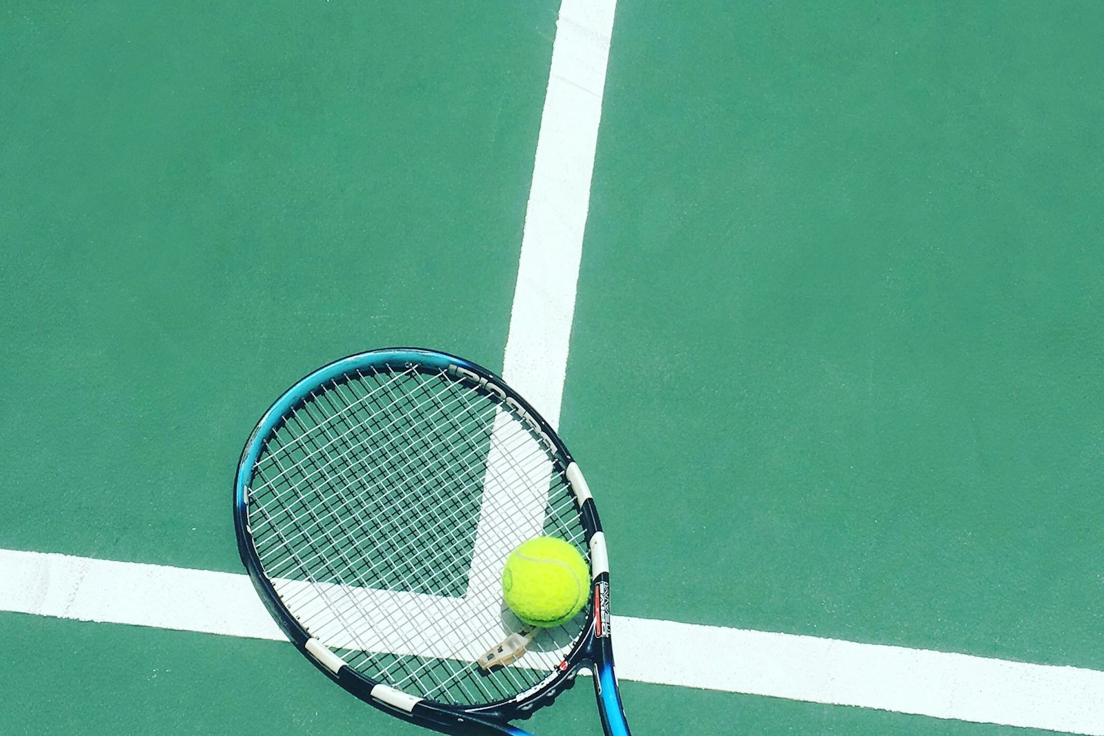 a racket and ball resting on a court line