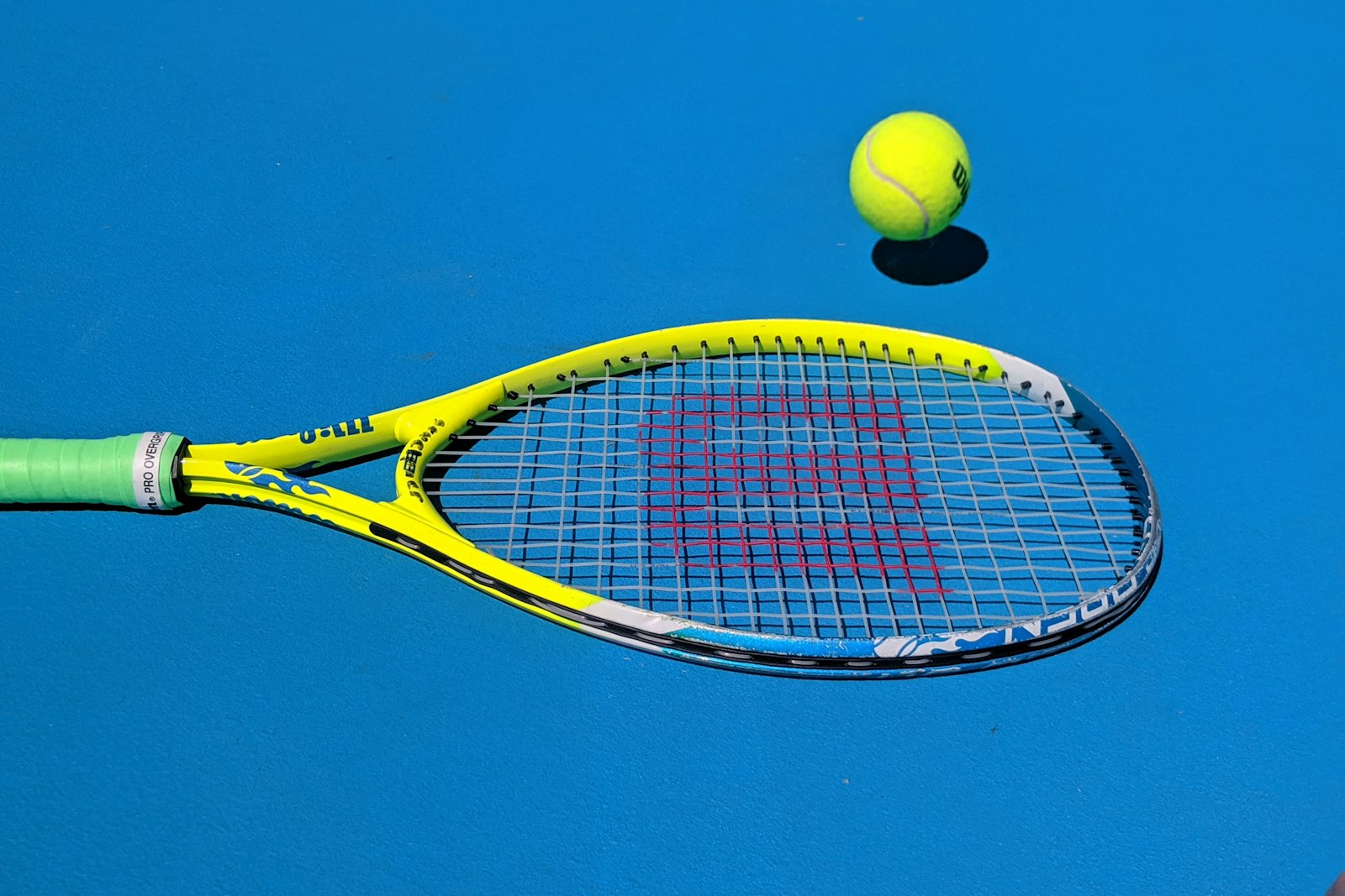 a racket and ball resting on a blue court